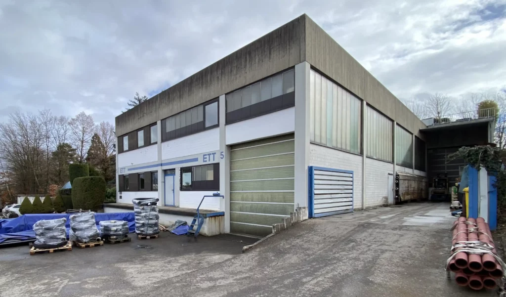 Firmengebäude der ETT Ersatzteil-Technik GmbH mit Lagerbereich und Förderrohren